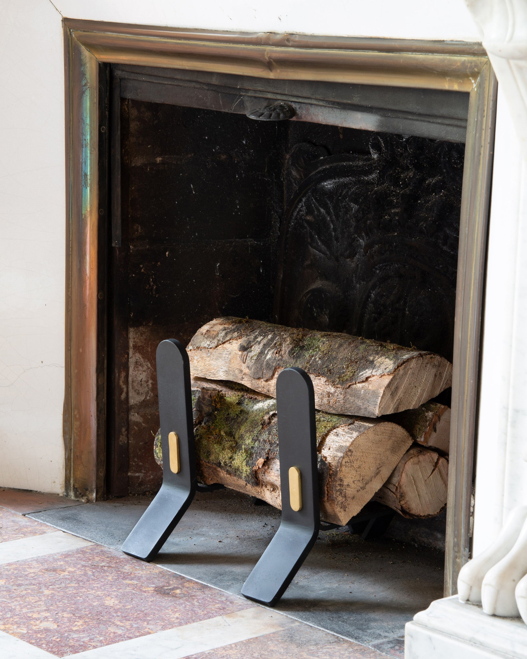 Fireplace with stacked logs and decorative metal firewood holders.