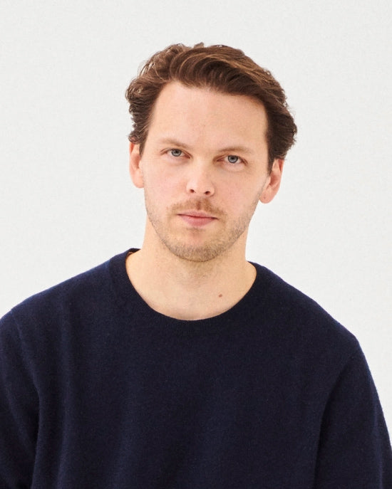 Man wearing a navy blue sweater against a light gray background
