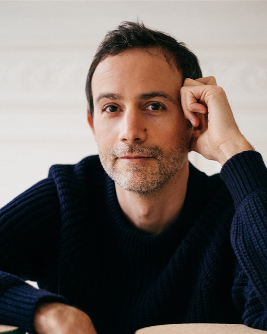 Man wearing a dark blue sweater against a plain background