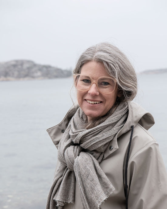 Woman wearing a scarf and glasses with a scenic background