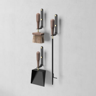Emma Wall in Graphite (charcoal black powder-coated steel, walnut wood and brass details) includes 3 wall hooks, a blow poker, and a shovel and brush.