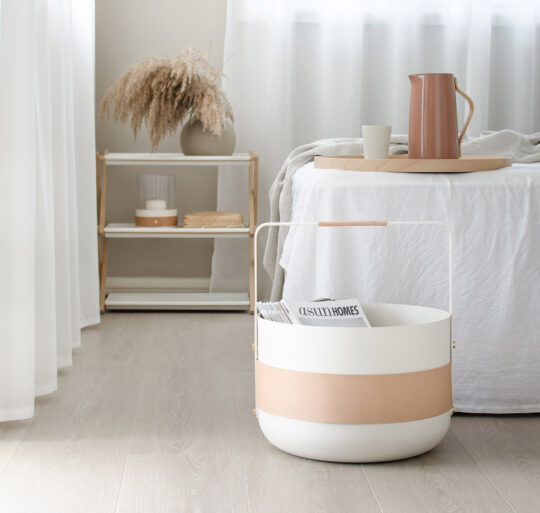 Emma Basket in Blanc (cream white powder-coated steel, beige leather and brass details) used for storing magazines.