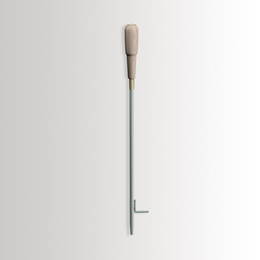 Emma Blow Poker in Lichen combines light green grey powder-coated steel, with a beech wood handle and brass details.