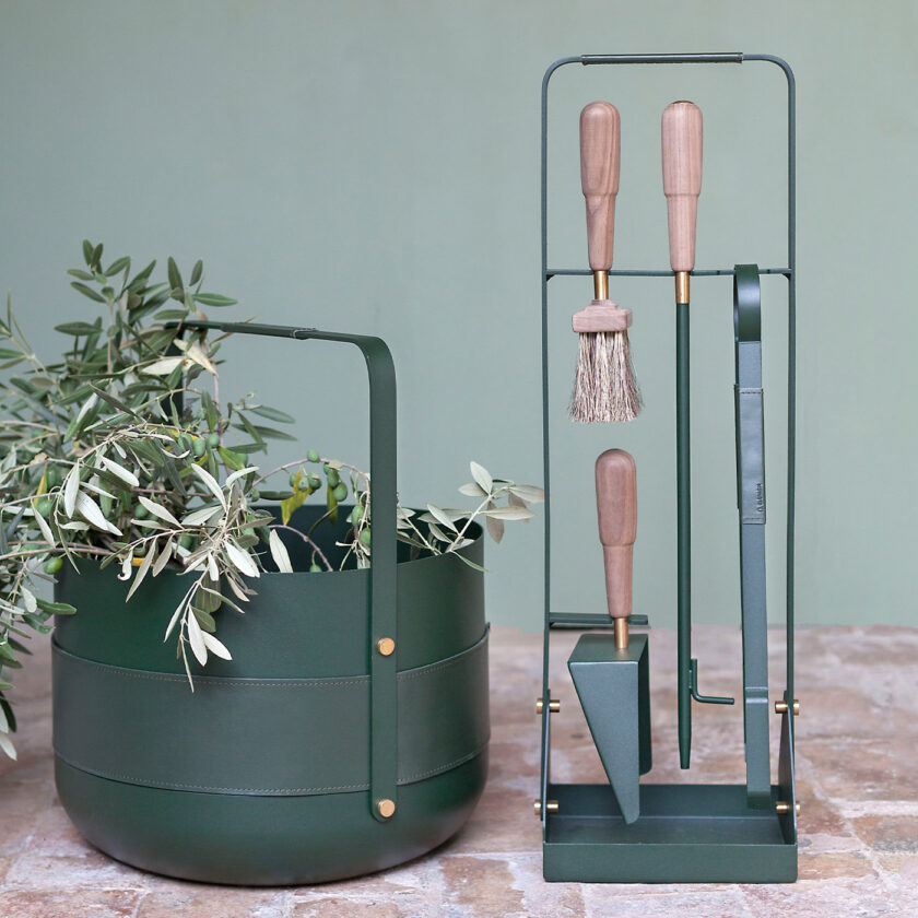 Emma Companion Set in Forêt (British racing green powder-coated steel, “Forêt” green leather, walnut wood handles and details in solid brass) outdoors with a basket in the same colour.