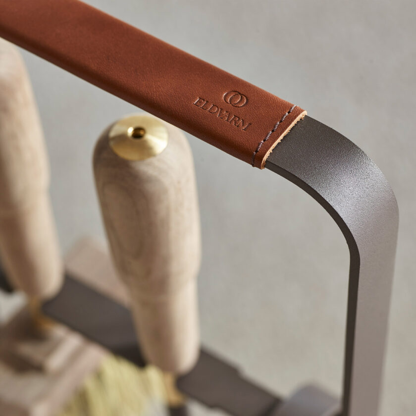 Close up of the leather of Emma Companion Set in Havane (dark warm grey powder-coated steel, “Havane” brown red leather, walnut wood handles and details in solid brass).