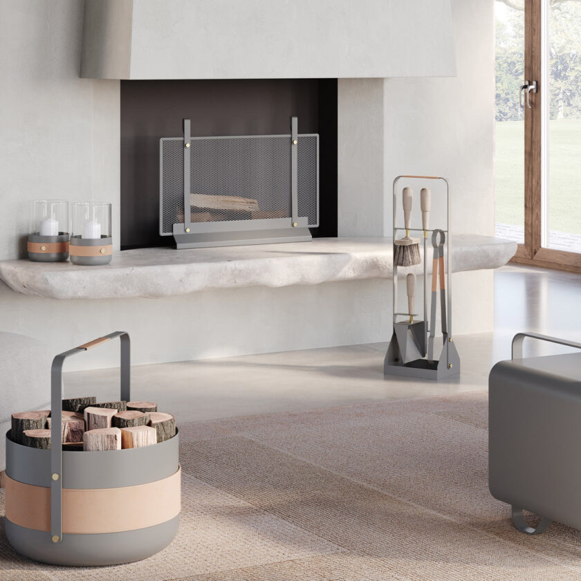 Emma Companion Set in Scandie (medium grey powder-coated steel, "Naturel” beige leather, beech wood handles and details in solid brass) in a living room with a fireplace and other products in the same colour.