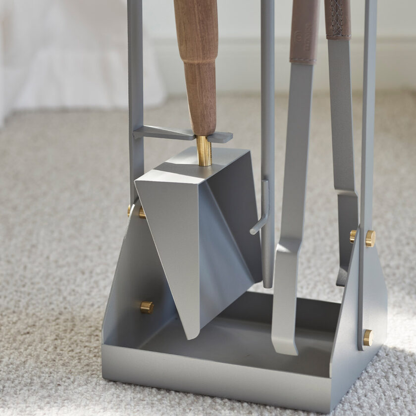 Close up of the base of Emma Companion Set in Paris (medium grey powder-coated steel, "Ellie” grey leather, walnut wood handles and details in solid brass).