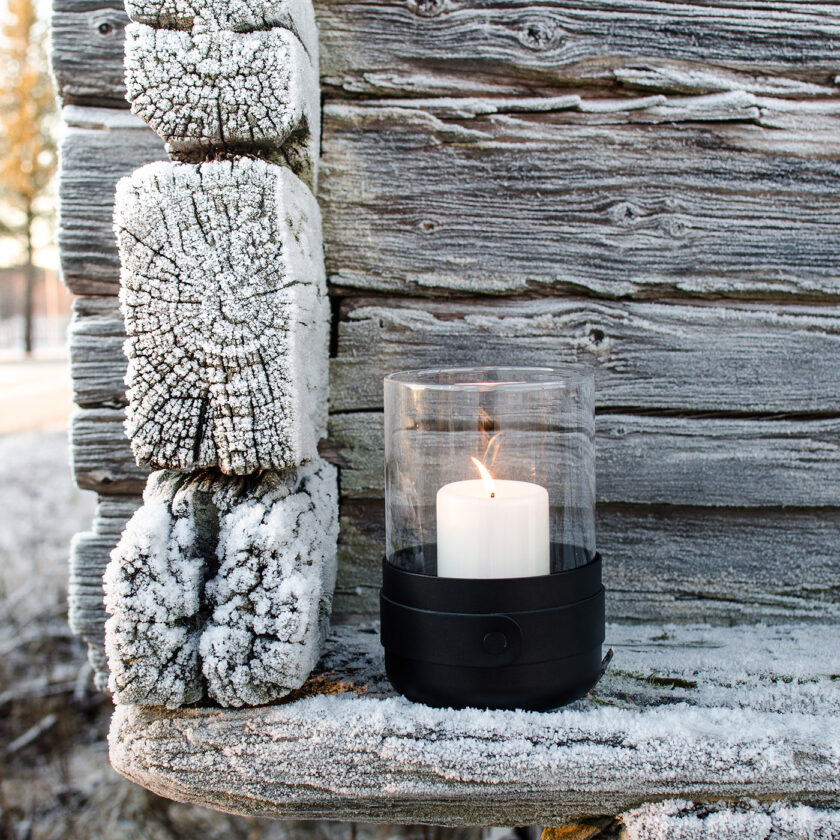 Emma Lantern in Noir (charcoal black powder-coated steel, “Noir” black leather, hand blown glass and black details) pictured outdoors.
