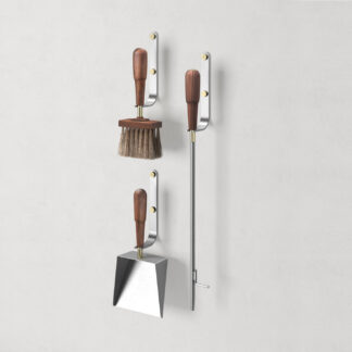 Emma Wall in Lumière (stainless steel, oiled walnut wood and brass details) includes 3 wall hooks, a blow poker, and a shovel and brush.