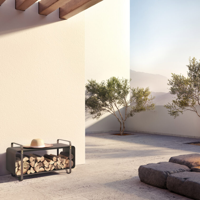 Ninne Bench Outdoor in the Classique (dark warm grey) colour shown next to a fire pit.