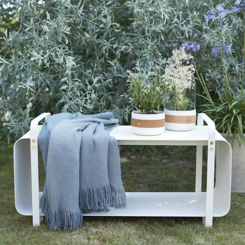 Ninne Bench in cream white powder-coated steel, outdoors with two Emma Lanterns in white (Blanc).