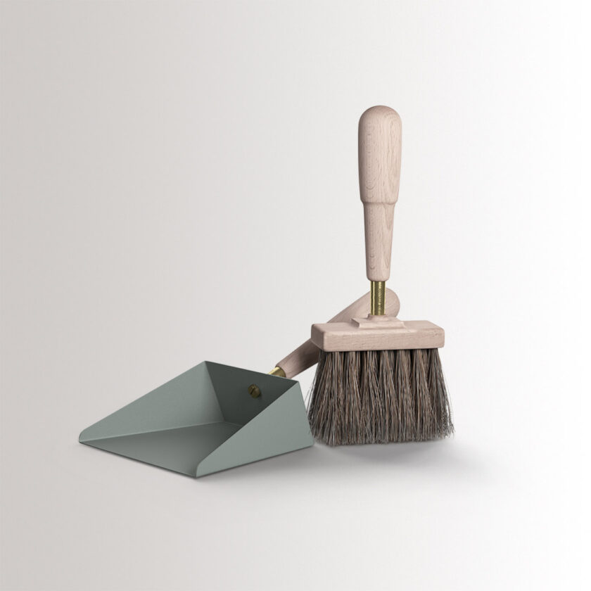 Emma Shovel & Brush in Lichen combines light green grey powder-coated steel, with beech wood and brass details, at an angle.