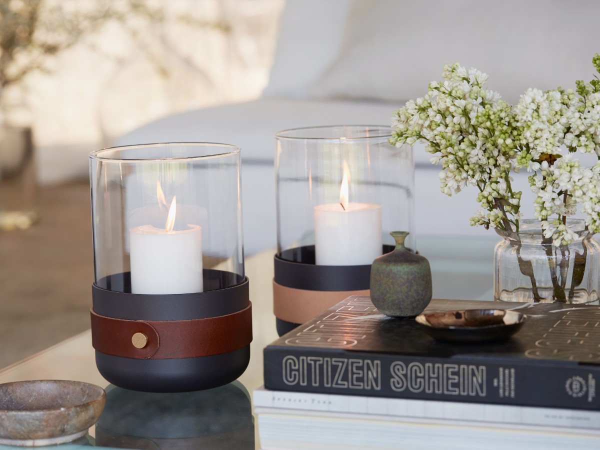 Pair of Emma Lanterns in Havane and Naturel with lit up candles next to flowers and a stack of books.