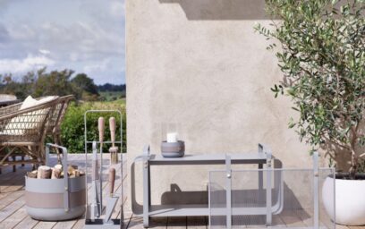 Emma Series in Paris (medium grey) outdoors including Basket with wood, Companion Set, Lantern with an unlit candle, Firescreen and Ninne Bench with galvanised steel.