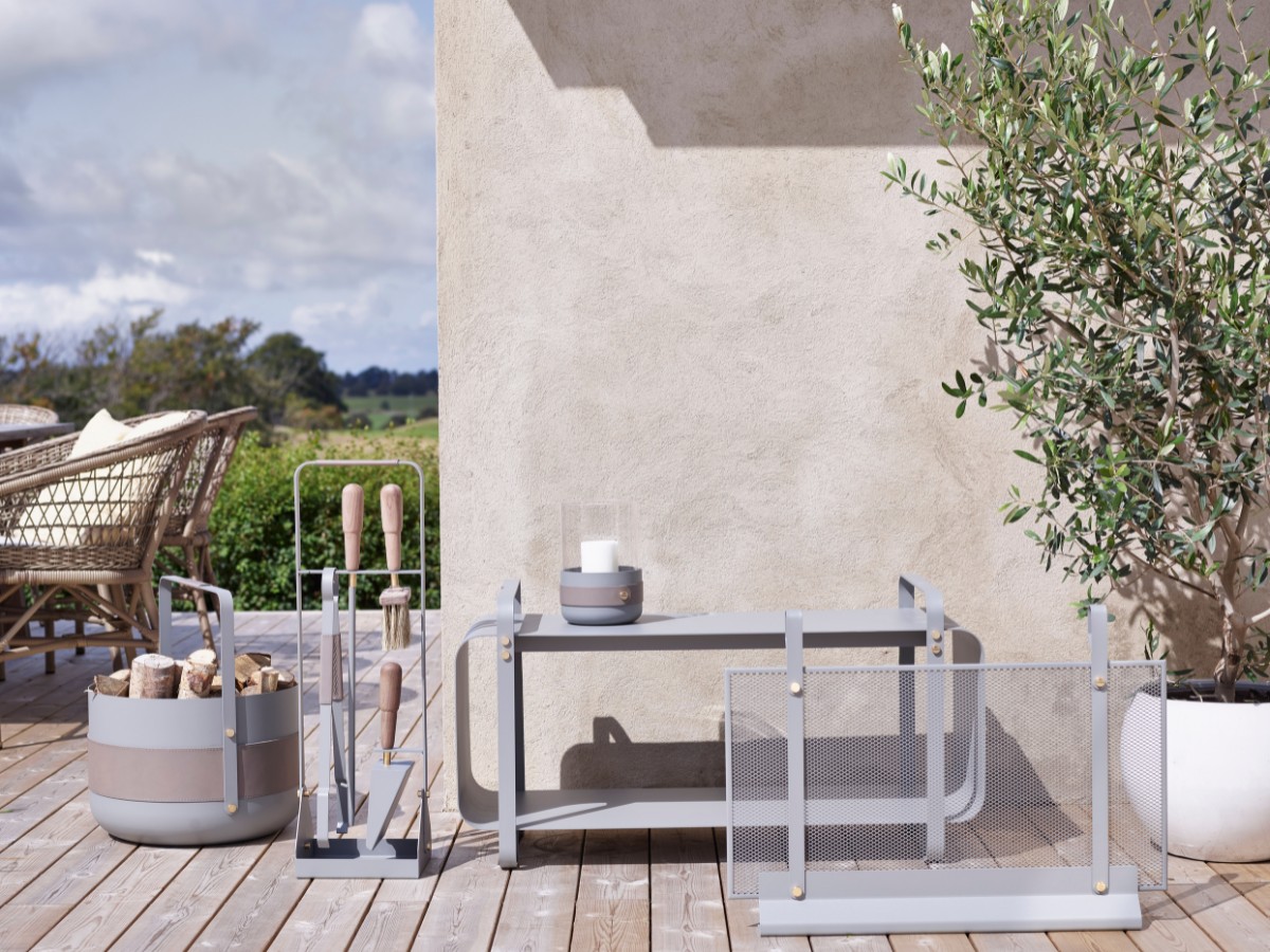 Emma Series in Paris (medium grey) outdoors including Basket with wood, Companion Set, Lantern with an unlit candle, Firescreen and Ninne Bench with galvanised steel.