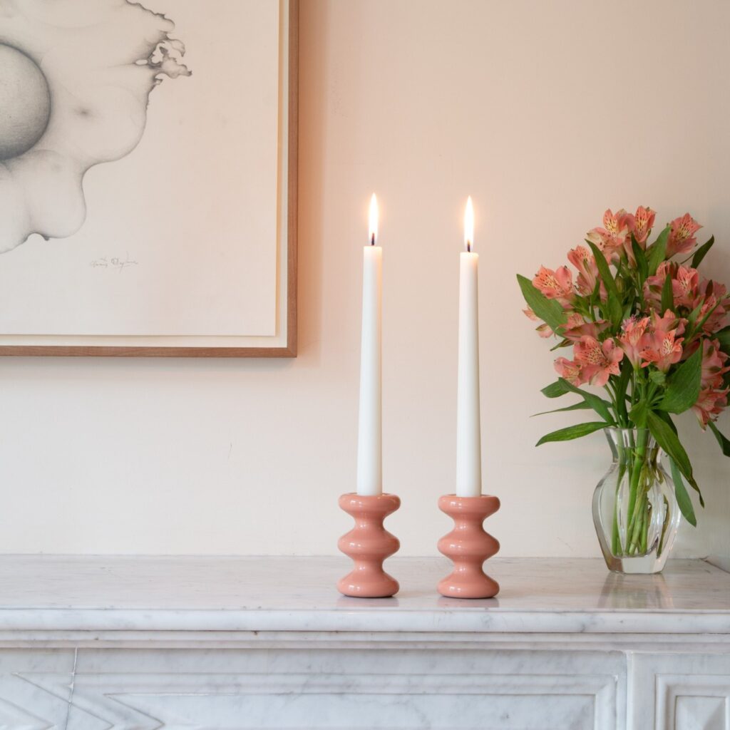 A pair of pink LouLou Candleholders on a mantelpiece, next to a vase.