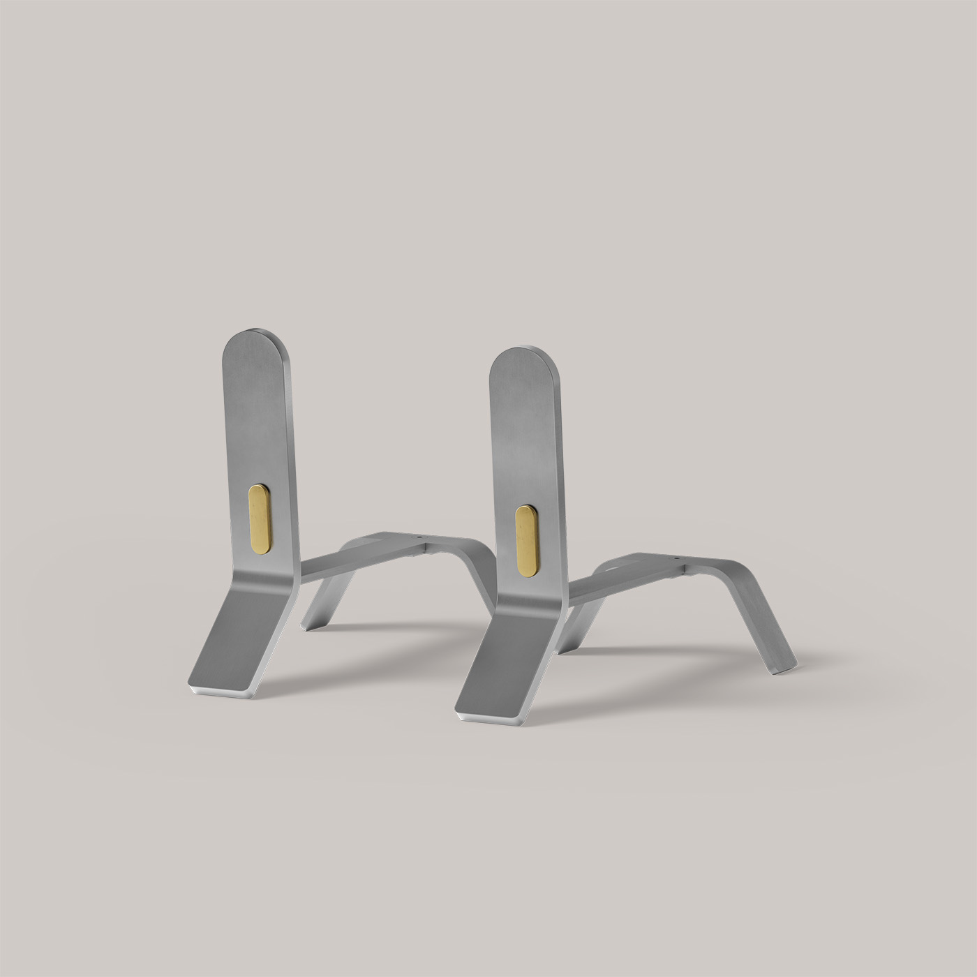 A pair of sleek, modern, silver bookends with a minimalist design, featuring slightly angled backrests and a gold accent on each. The bookends are positioned parallel to each other on a flat, light gray surface.