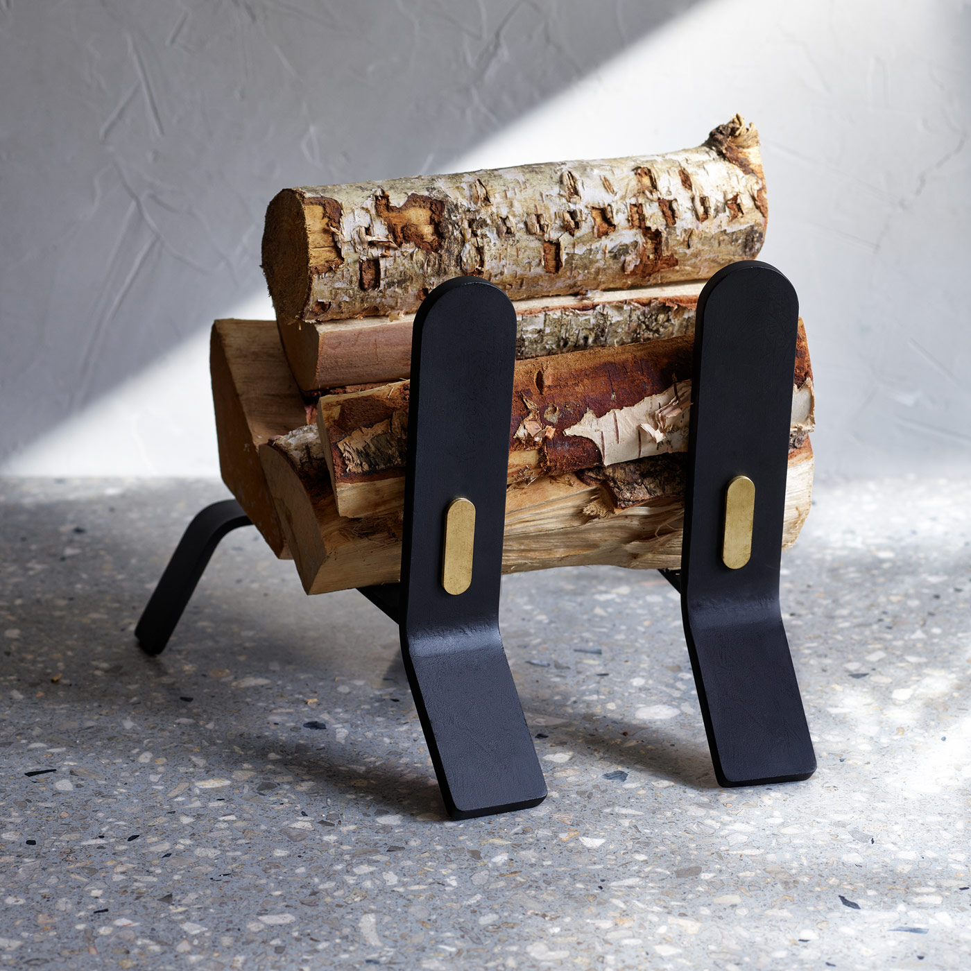 Cooper Fire dogs in Noir (charcoal black powder-coated steel with brass details) with wood on top of it.