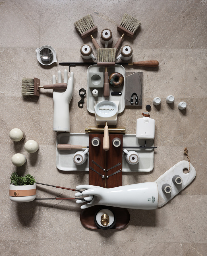 The Multi-Tasker - An imaginative collage of items coming together to create a figure, created by Philip Howlett of Herringbone Design. It features several Eldvarm products, including a Blanc Emma Lantern, a Blanc Shovel, a Brass Lucie Candle Holder, and a Classique Blow Poker.