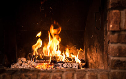 A brick fireplace with a fire burning it.