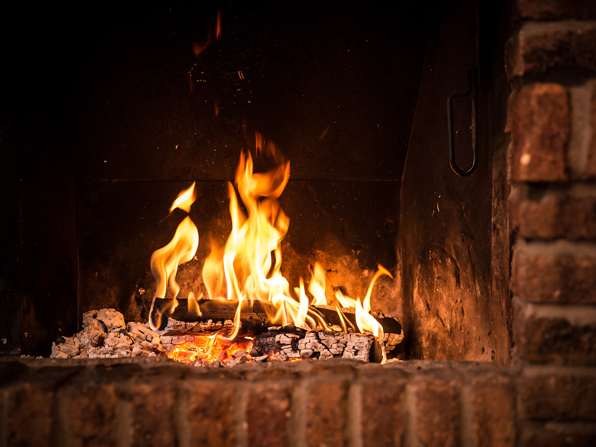 A brick fireplace with a fire burning it.