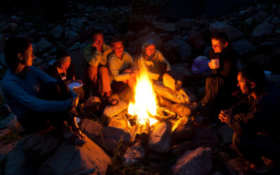 A group of people circled around a bonfire in the evening.